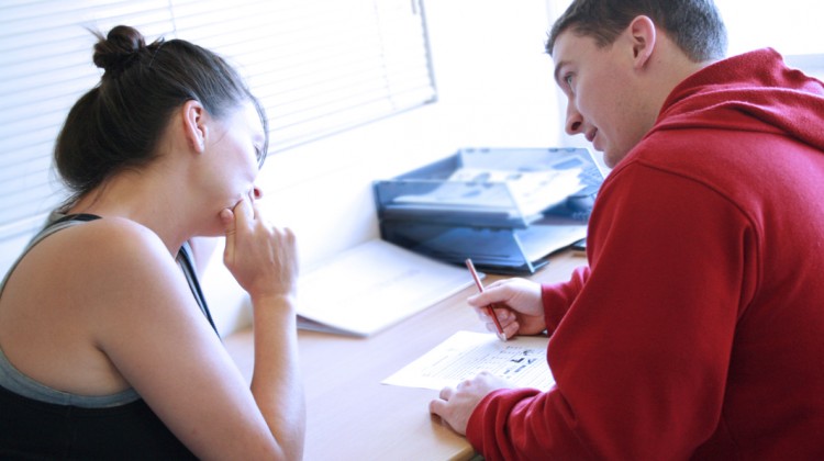 Personal_trainer_assessing_a_client's_goals_and_needs_as_they_write_a_fitness_programme