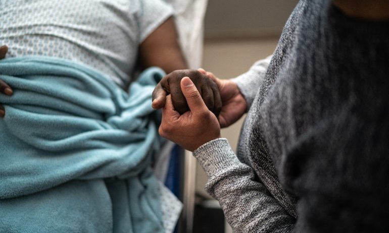 Person holding person's hand at the hospital