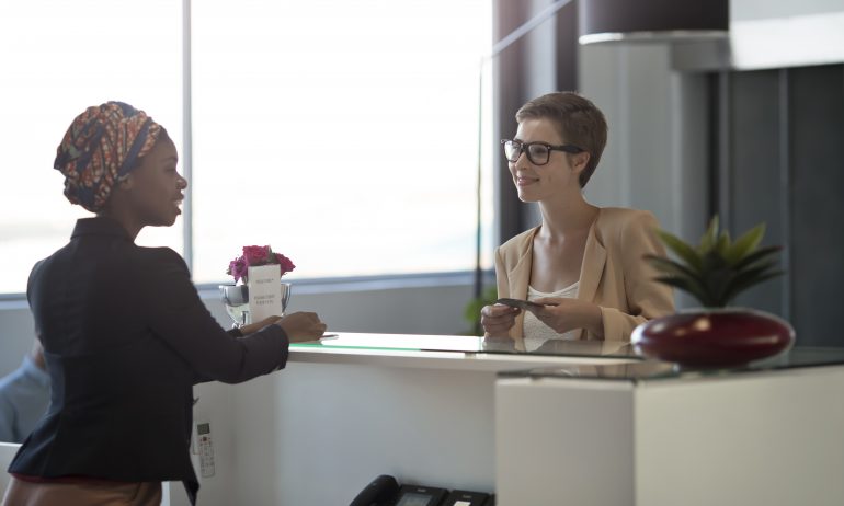 Businesspeople checking in to hotel in the lobby to maintain hotel elite status