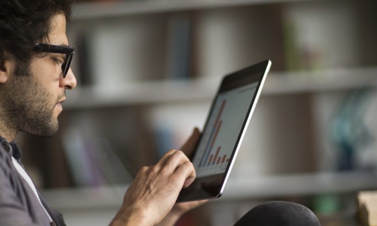 Young man looks at graph on tablet computer