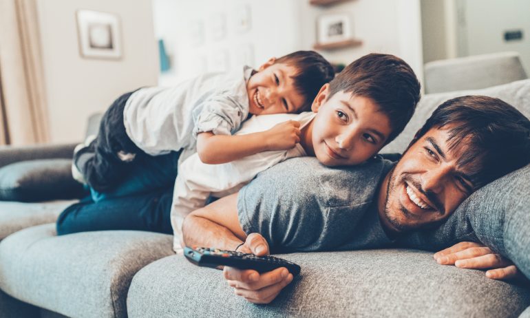 Father and two young sons playing on sofa