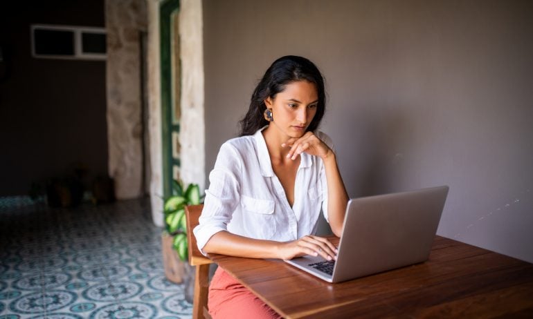 A woman doing financial research on a laptop — perhaps searching for high-dividend ETFs.