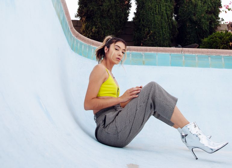 Sitting in an empty pool, Wong-Wear glances sideways while sporting a cropped top, baggy pants and silver stiletto boots.