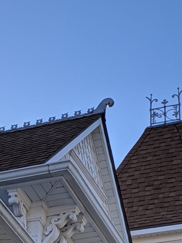 Cutout rounded shapes line the top of the gabled roof.