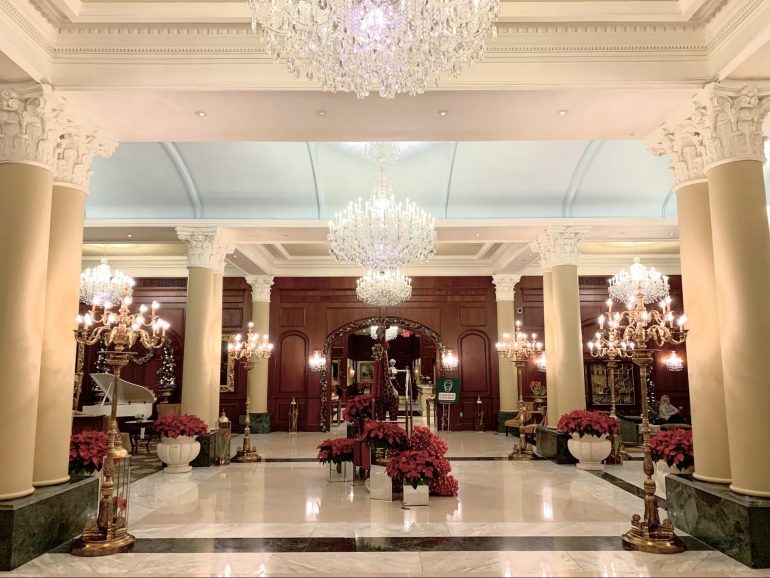 Chandeliers and floral arrangements abound in a grand indoor hall.