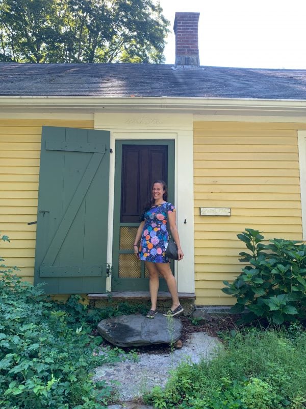 The author standing outside the front door of her yellow house.