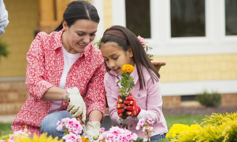 mother and daughter planting flowers in yard