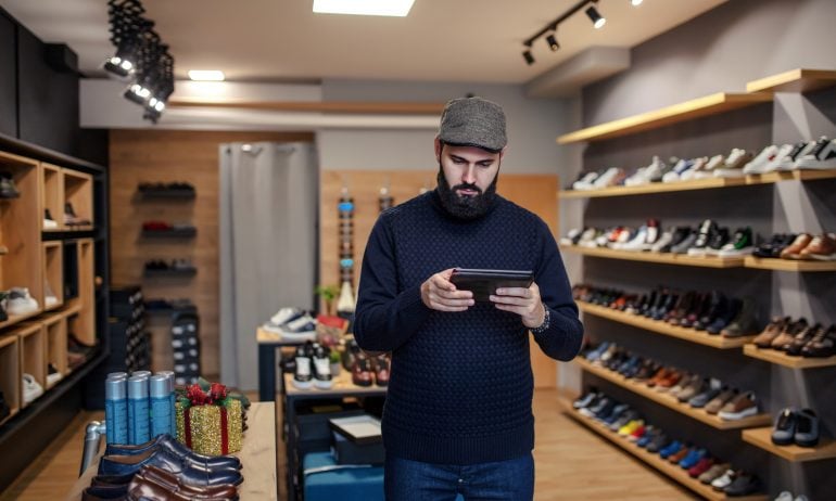 Male Owner Of Online Shoe Business Using Digital Tablet
