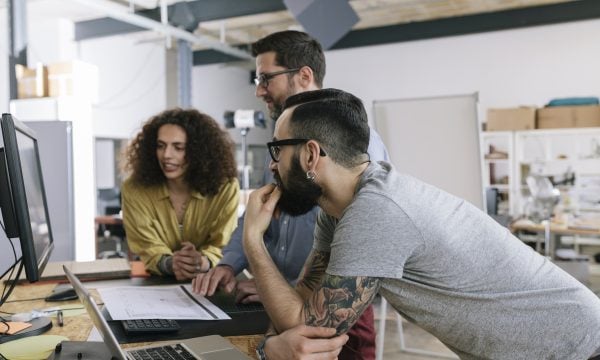 Small group of co-workers working together in a startup business office space.