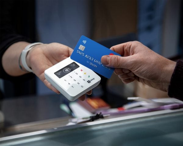 A customer swipes a blue credit card with the SumUp credit card reader.