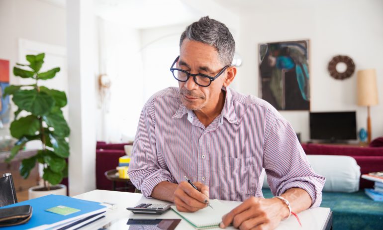 Mature man wearing eyeglasses working on personal finances at home