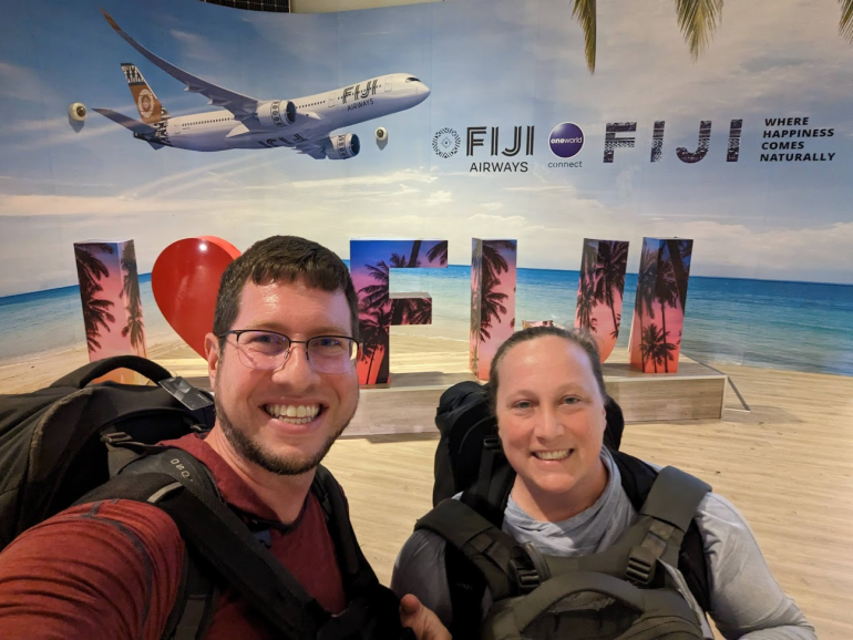 JT Genter and his wife Katie take selfie in front of an I Love Fiji sign.