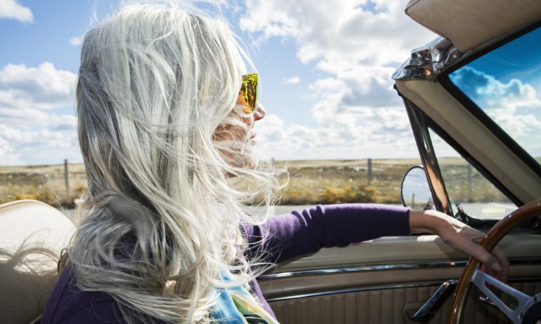 Woman driving a convertible on a sunny day.