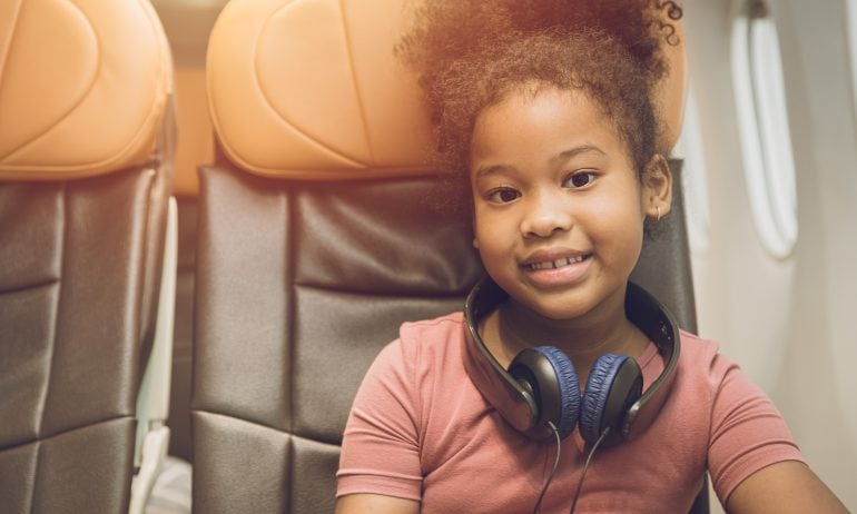 children traveling alone or unaccompanied minor. child girl fly travel sitting alone in flight cabin seat happy smile.
