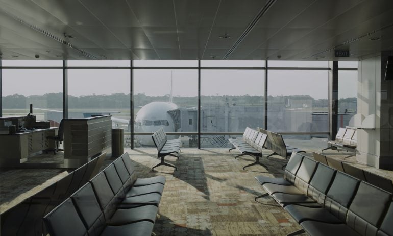 Empty airport lounge with plane outside.