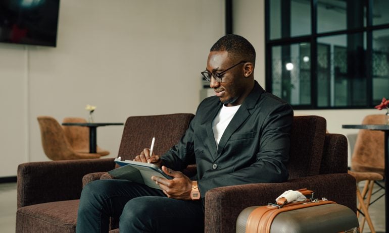 Businessman Uses tablet Waiting for a Flight, Traveling Entrepreneur Remote Work Online Sitting in a Boarding Lounge of Airline Hub.