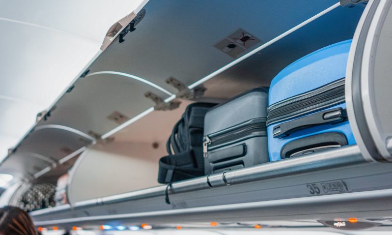 Overhead locker on airplane,Passenger put cabin bag cabin on the top shelf. Travel concept