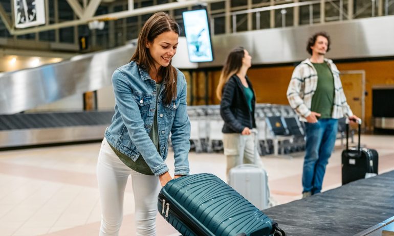 Beautiful young woman picking up her luggage from the baggage carousel at the airport in Malmo in Sweden.