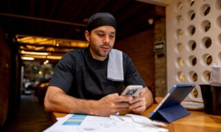 Latin American chef doing the books at a restaurant after closing and using an app on his cell phone