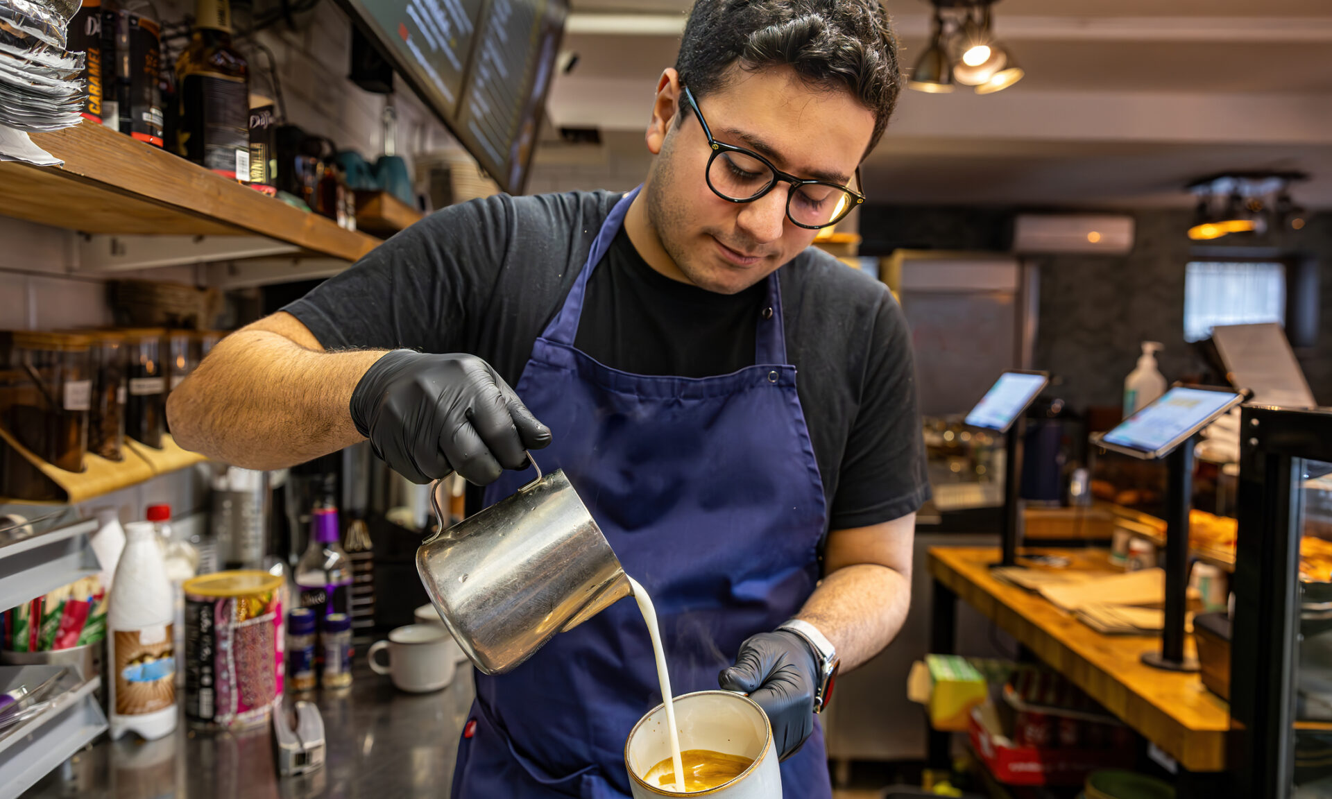 A young male barista in a coffee shop or cafe.