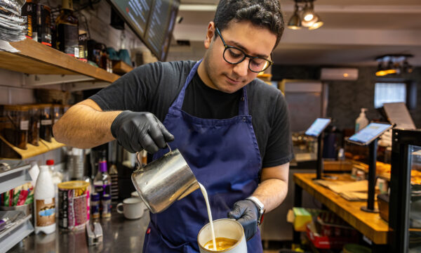 A young male barista in a coffee shop or cafe.