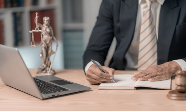 Lawyer writing in a notebook next to laptop