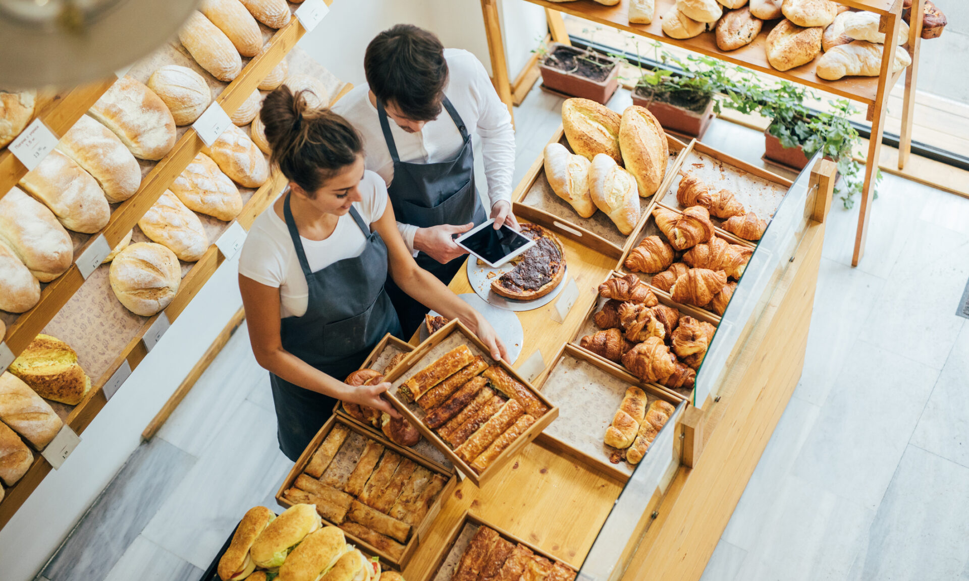 Two employees using a tablet at a bakery.