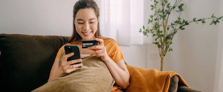 Smiling young woman using her first credit card to shop online.