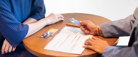 The bank clerk is presenting the benefit of the credit card to a customer who applied for a credit card service at the office.