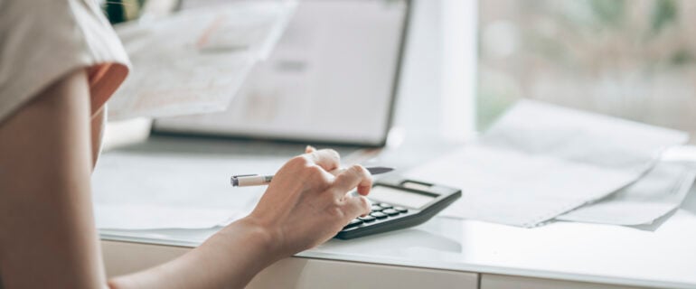 Woman using a calculator to track expenses for her budget.