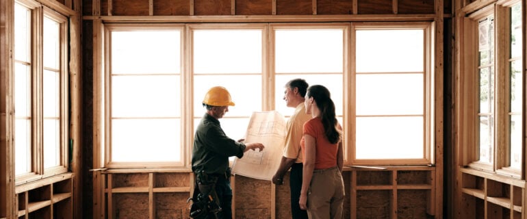 Husband and wife consulting with a architect inside a home under construction.