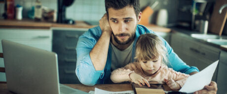 Father contemplates debt consolidation while sitting at kitchen table with daughter.