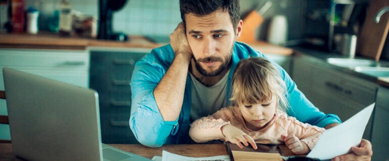 Father contemplates debt consolidation while sitting at kitchen table with daughter.