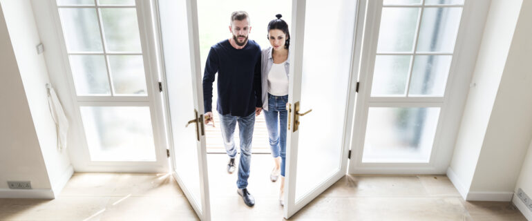 Couple thinking about buying their first home enter a potential house.
