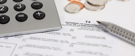 A T4 slip sits on a table surrounded by a pen and calculator.