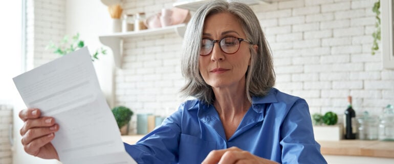 Mature woman at kitchen table considers annuities as part of her retirement strategy.