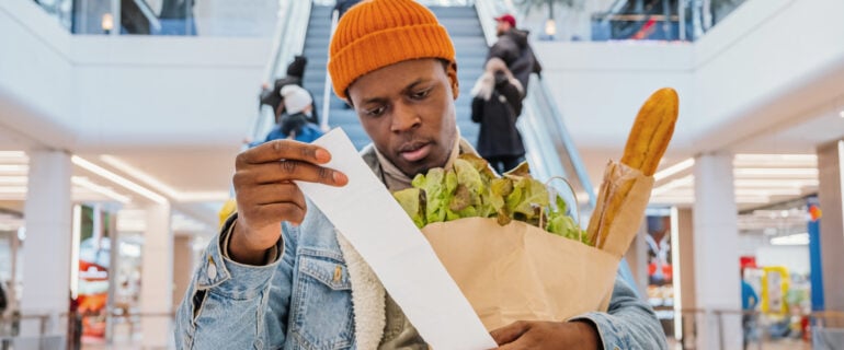 Black man thinks about inflation while examining his grocery bill.
