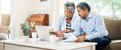 Older couple on couch discussing defined benefit vs defined contribution pension plans.