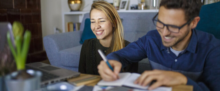 Smiling couple checks their joint account on a laptop.