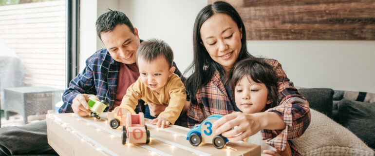 Parents playing with their two children in the living room.