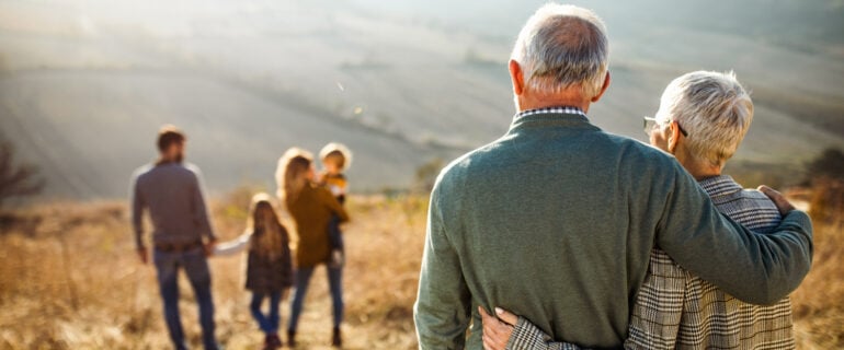 Older couple standing outdoors thinks about naming their beneficiaries.