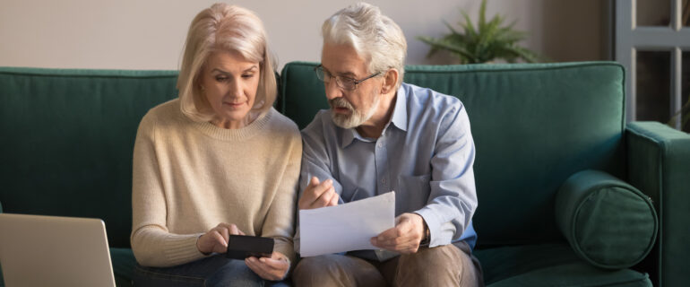 Mature couple discussing loan principal and interest in their living room.