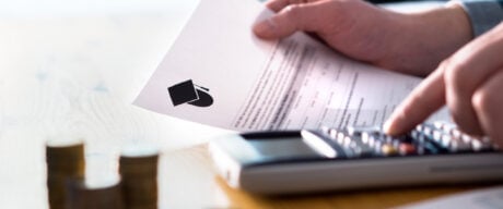 Man calculates tuition tax credit while holding a paper tax form.