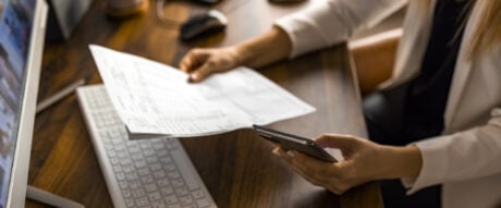 A woman sits at her table with computer and tax forms and receipts to determine if she will receive a tax refund.