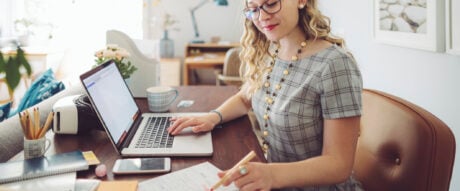 Woman seated at her desk reviewing receipts and tax documents to claim a deduction.