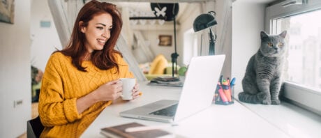 Women buying cryptocurrency on her laptop while her cat looks on.