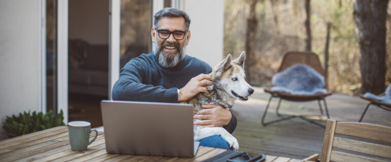 Mature man sitting outside with dog, researching LIRA options.