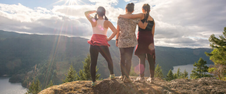 Mother and teenage daughters enjoying view from mountain summit.