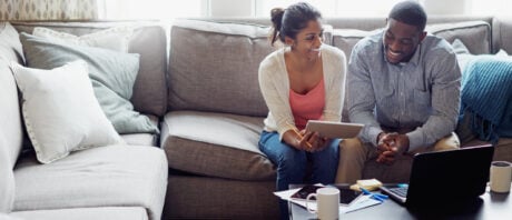 Young couple discuss the RRSP deadline while sitting on their couch.