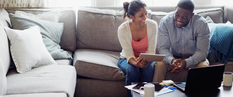 Young couple discuss the RRSP deadline while sitting on their couch.